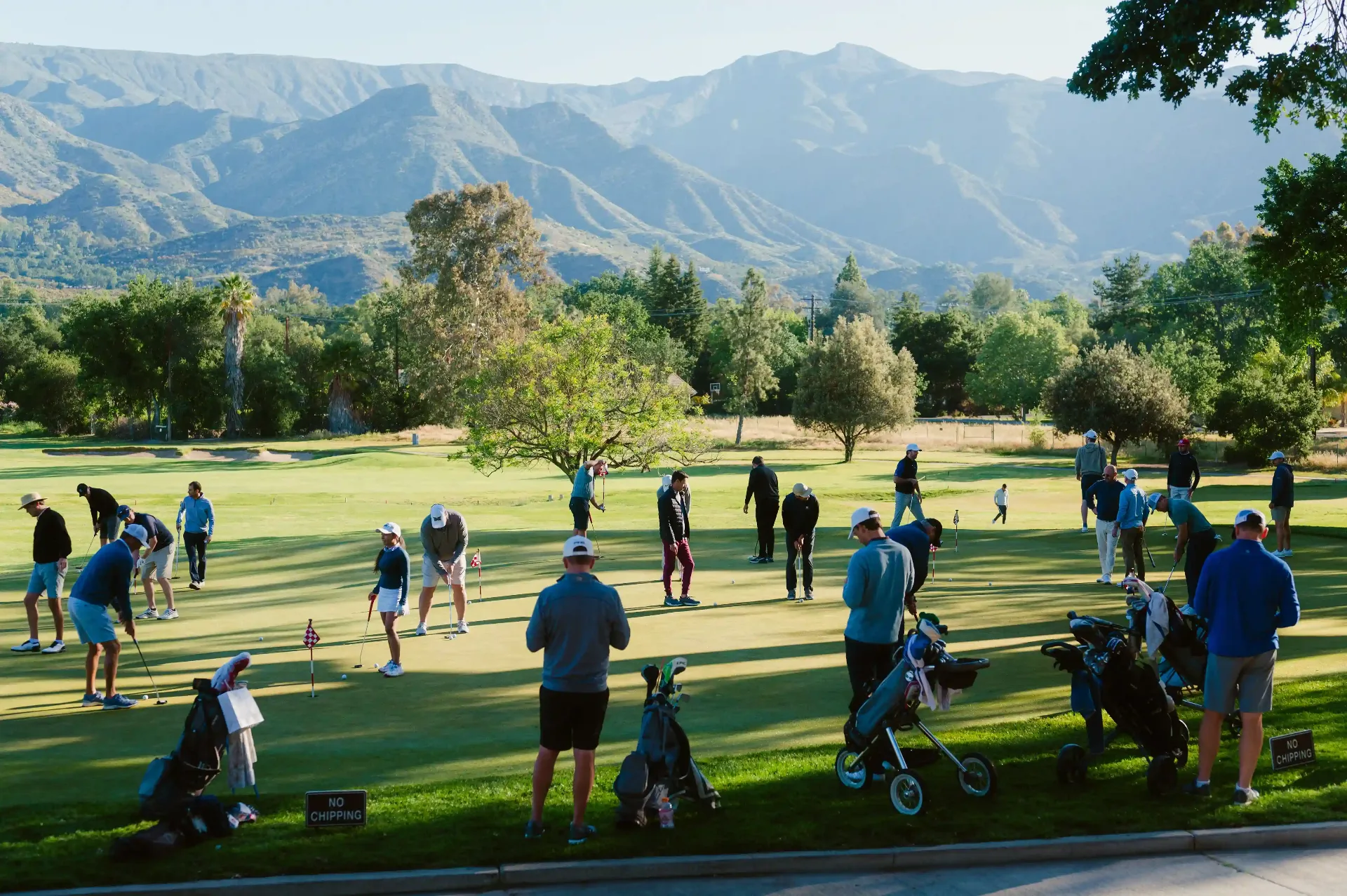 Players on the putting green at the Aurora Golf Event with mountain backdrop