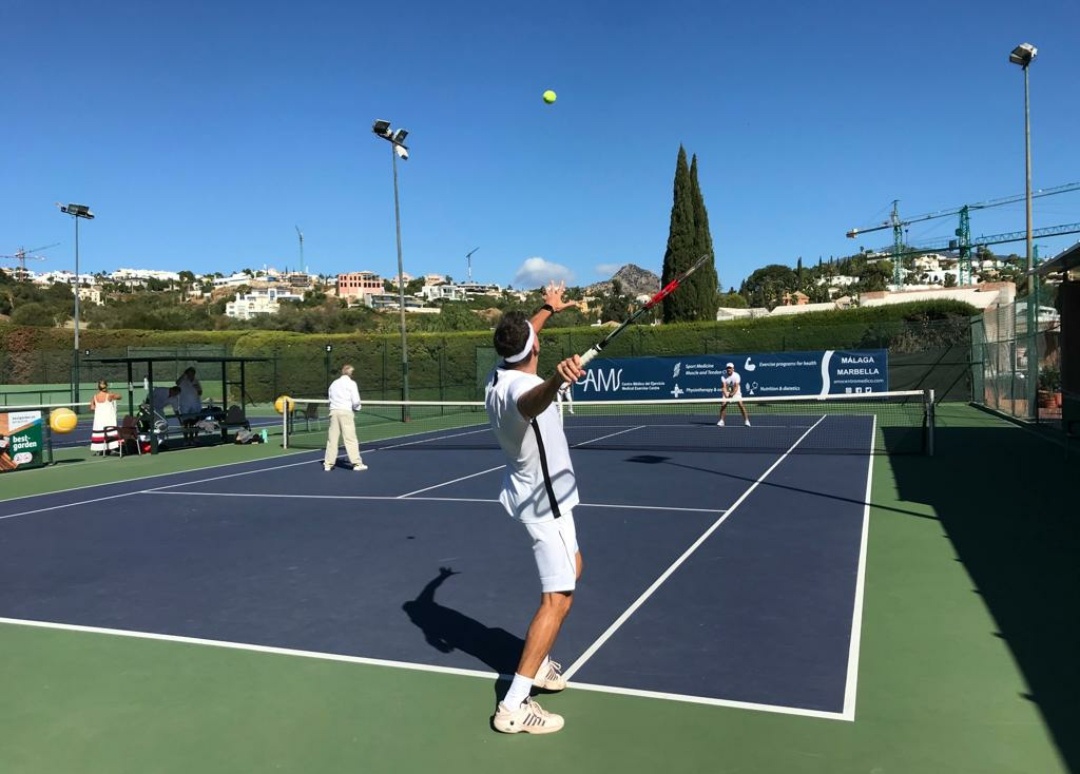 Player serving on a Marbella tennis court at the Aurora Tennis Mix In